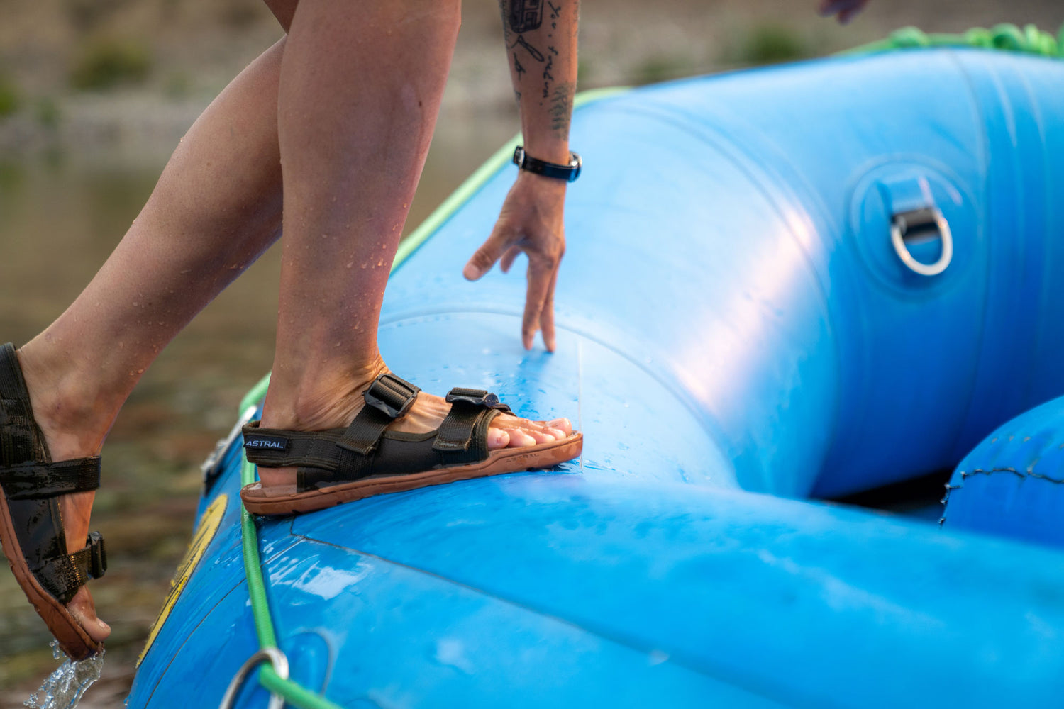Person stepping onto a raft wearing Astral Webber Olive Green