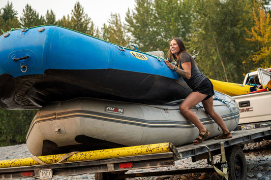 Person pushing a raft off a trailer wearing Astral Webber Olive Green